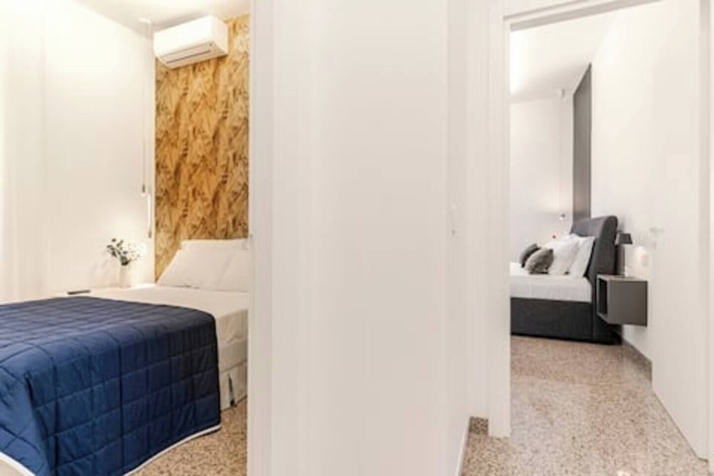 Ein Hotelzimmer mit Bett, Nachttisch und Wand-Klimaanlage.