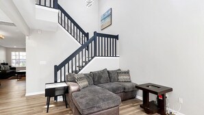 Ein modernes Wohnzimmer mit einem Ecksofa, einem Holztisch und einer Treppe.