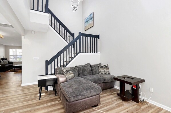 Una sala moderna con un sofá modular, una mesa de centro de madera y una escalera.