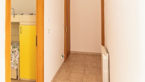 Un pasillo con un radiador, una puerta y un armario amarillo al fondo.