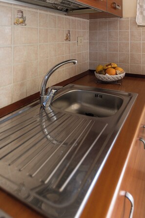 Una cocina con un lavamanos de acero inoxidable, una encimera de madera y un frutero.