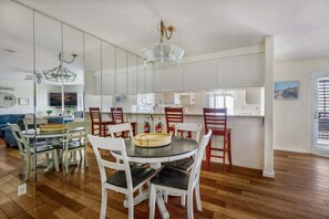 A dining area with a round table, chairs, and a hanging light fixture. - Beachfront 2BR Harbor Condo w/ Ocean View Balcony (Oceanside)