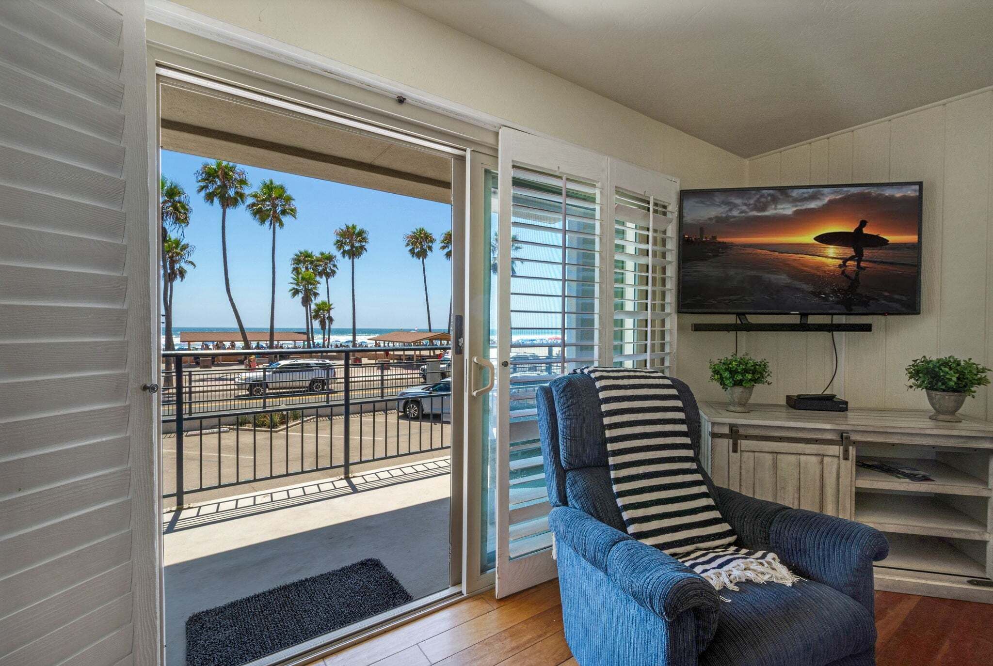 Une chambre avec vue sur la plage, une télévision et une chaise à rayures.