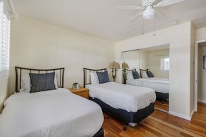 A hotel room with two beds, a ceiling fan, a mirror, and a nightstand with a lamp. - Beachfront 2BR Harbor Condo w/ Ocean View Balcony (Oceanside)