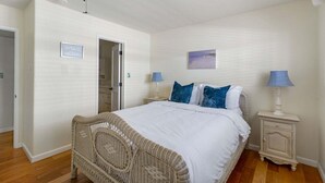 Una camera da letto con un letto, due comodini, una ventola a soffitto e una porta che dà su un'altra stanza.