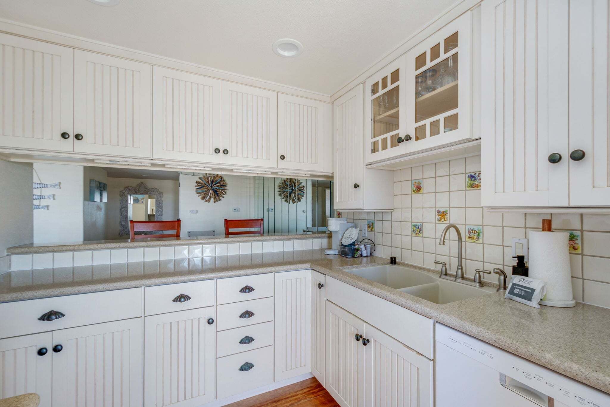 Una cocina con armarios blancos, un lavamanos doble y un salpicadero decorativo.
