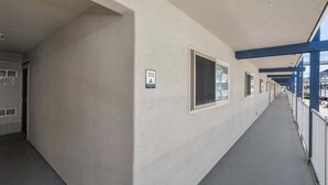Un corridoio con diverse finestre, una targa che indica la stanza 212A e una ringhiera blu sulla destra.