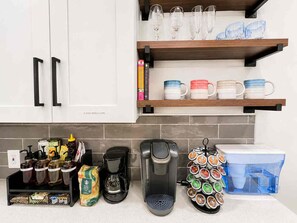 A kitchen with white cabinets, a coffee maker, a mug rack, and a spice rack. - Atlanta Oasis with a Spa Suite, Huge Backyard, Fire Pit & Hammocks (Atlanta)
