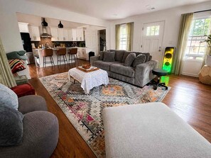 A modern living room with a sofa, ottoman, coffee table, and a patterned rug. - Atlanta Oasis with a Spa Suite, Huge Backyard, Fire Pit & Hammocks (Atlanta)
