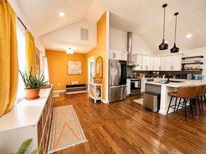 A modern kitchen with a central island, stainless steel appliances, and a dining area with bar stools. - Atlanta Oasis with a Spa Suite, Huge Backyard, Fire Pit & Hammocks (Atlanta)
