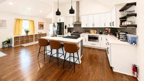 A modern kitchen with white cabinetry, a central island with bar stools, and pendant lighting. - Atlanta Oasis with a Spa Suite, Huge Backyard, Fire Pit & Hammocks (Atlanta)