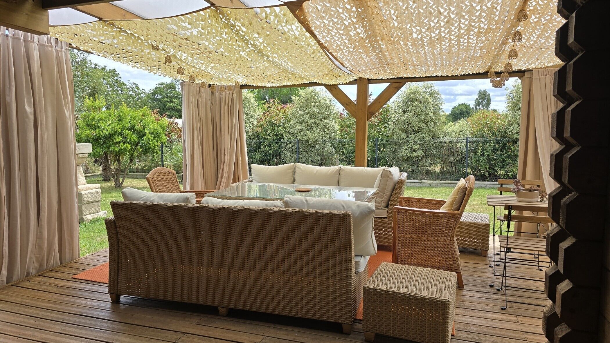 An outdoor patio with wicker furniture, a glass-top table, and a pergola with a woven canopy.
