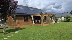 Een houten huis met een overdekte veranda en een gazon.