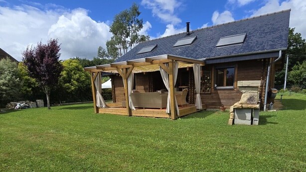Een huis met een overdekte patio, een stenen openhaard en een groot gazon.
