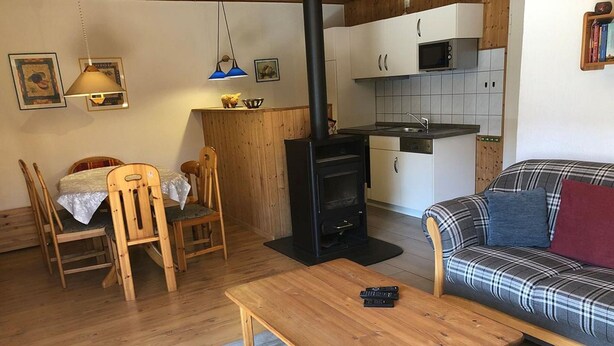 Ein gemütliches Wohnzimmer mit einer Couch, einem Holztisch und einem Essbereich mit Stühlen und Tisch.