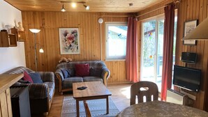 Ein gemütliches Zimmer mit einem karierten Sofa, einem Holztisch und einem an der Wand befestigten Fernseher.