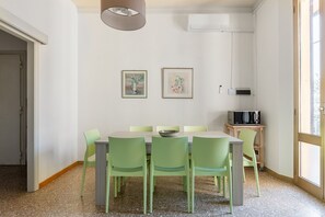 A dining area with a table, chairs, artwork, and a microwave. - Irnerio Apts - Olive Green by Wonderful Italy (Bologna)