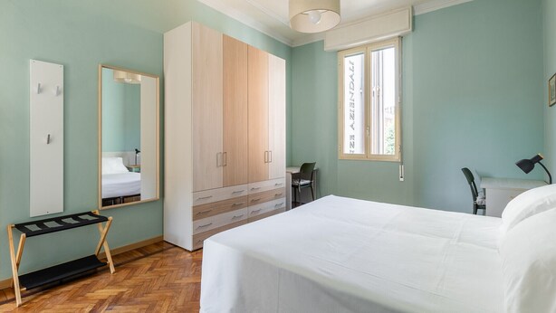 Ein Schlafzimmer mit einem Bett, einem Kleiderschrank, einem Schreibtisch und einem Stuhl.