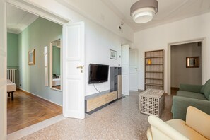 A living room with a television, a sofa, a coffee table, and a bookshelf. - Irnerio Apts - Olive Green by Wonderful Italy (Bologna)