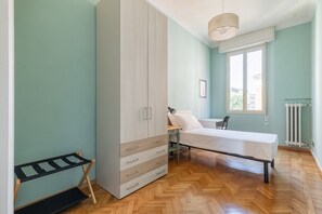 A bedroom with a bed, a wardrobe, a desk, a chair, and a radiator. - Irnerio Apts - Olive Green by Wonderful Italy (Bologna)