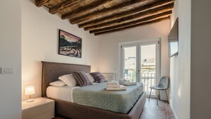 A bedroom with a bed, nightstand, and a view of the outside. - CS Spanish Steps Boutique A Apartment (Rome)