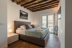 A bedroom with a bed, nightstand, and a view of the outside. - CS Spanish Steps Boutique A Apartment (Rome)