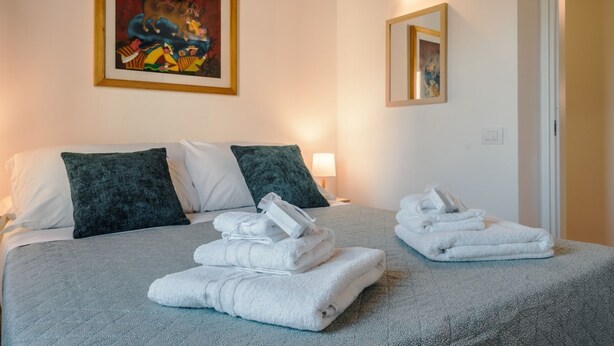 A hotel room with a bed, pillows, a painting, and towels. - CS Spanish Steps Boutique A Apartment (Rome)