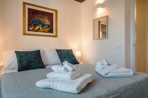 A hotel room with a bed, pillows, a painting, and towels. - CS Spanish Steps Boutique A Apartment (Rome)