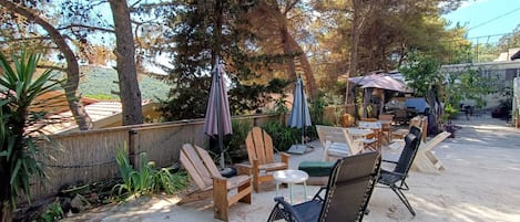 An outdoor patio with wooden furniture, a round table, and umbrellas.