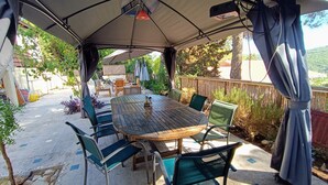Eine Terrasse im Freien mit Tisch und Stühlen unter einem Zelt.