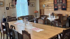 A dining area with a wooden table, chairs, and a chandelier. - Yöveden Ateljeekoti (Mikkeli)