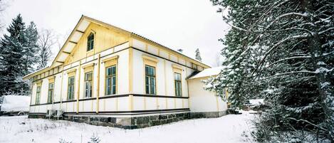 A two-story building with a symmetrical facade, large windows, and a snow-covered landscape.