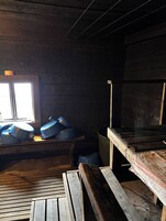 Interior rústico de una cabaña con un banco de madera, una ventana y una mesa con recipientes azules.