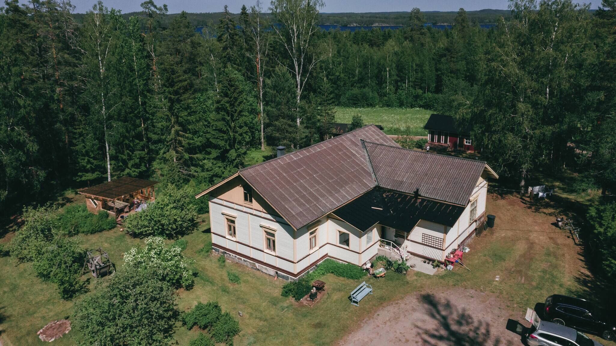 Ein zweistöckiges Haus mit geneigtem Dach, umgeben von dichtem Wald.