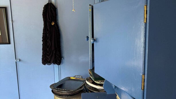 A room with a blue cabinet, a hanging garment, and a decorative ceiling. - Yöveden Ateljeekoti (Mikkeli)