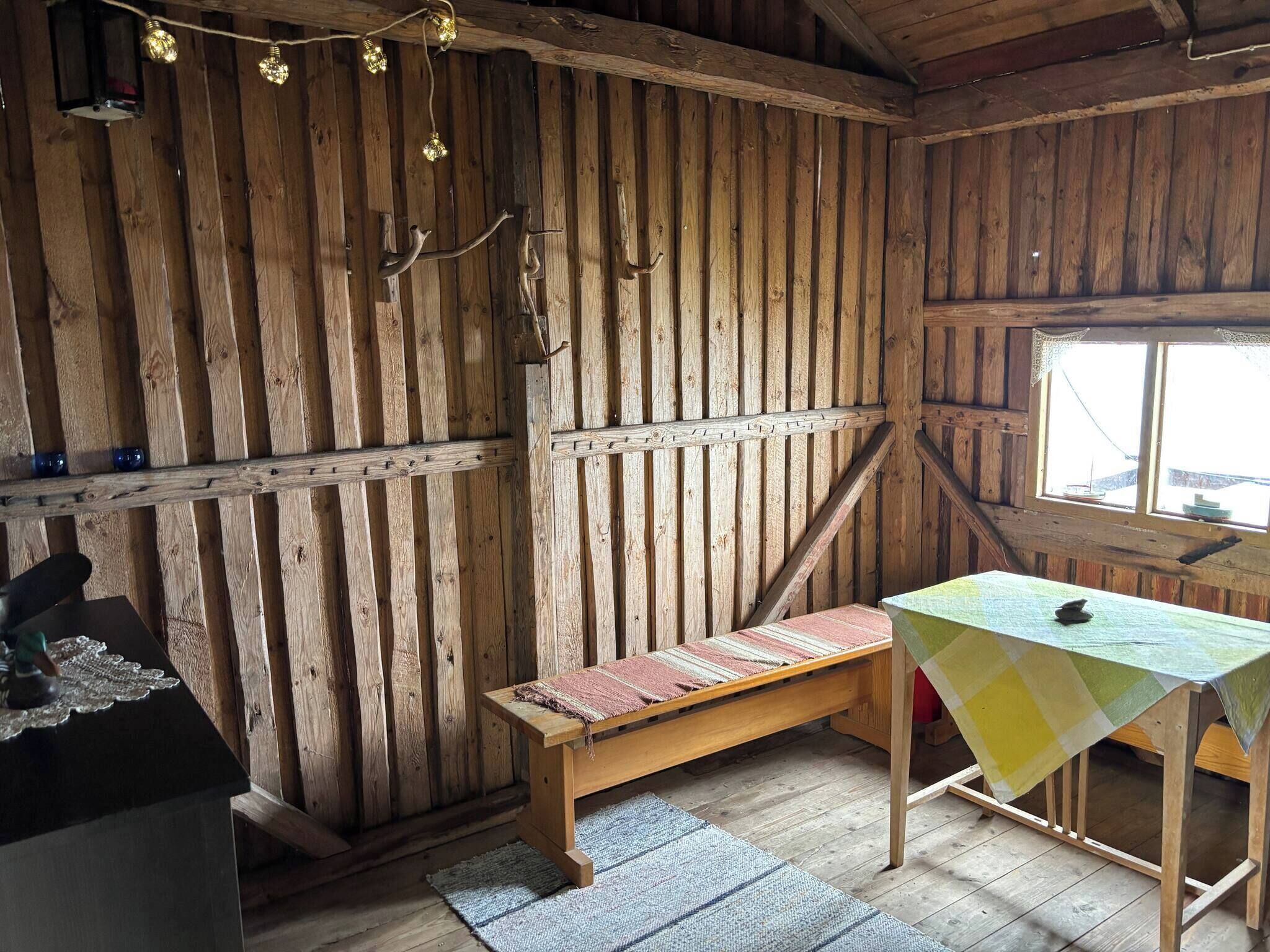 Una stanza in legno dall'aspetto rustico, con una panca, un tavolo con tovaglia a scacchi e una finestra vista panoramica.
