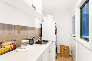 A compact kitchen with a sink, a refrigerator, and a window. - Genesta Ocean Sands Cowes (Cowes)