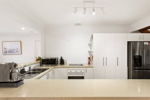 A modern kitchen with white cabinets, stainless steel appliances, and a granite countertop. - Genesta Ocean Sands Cowes (Cowes)