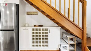 A kitchen with a stainless steel refrigerator, a wooden staircase, and a white cabinet with a grid of shelves. - Genesta Ocean Sands Cowes (Cowes)