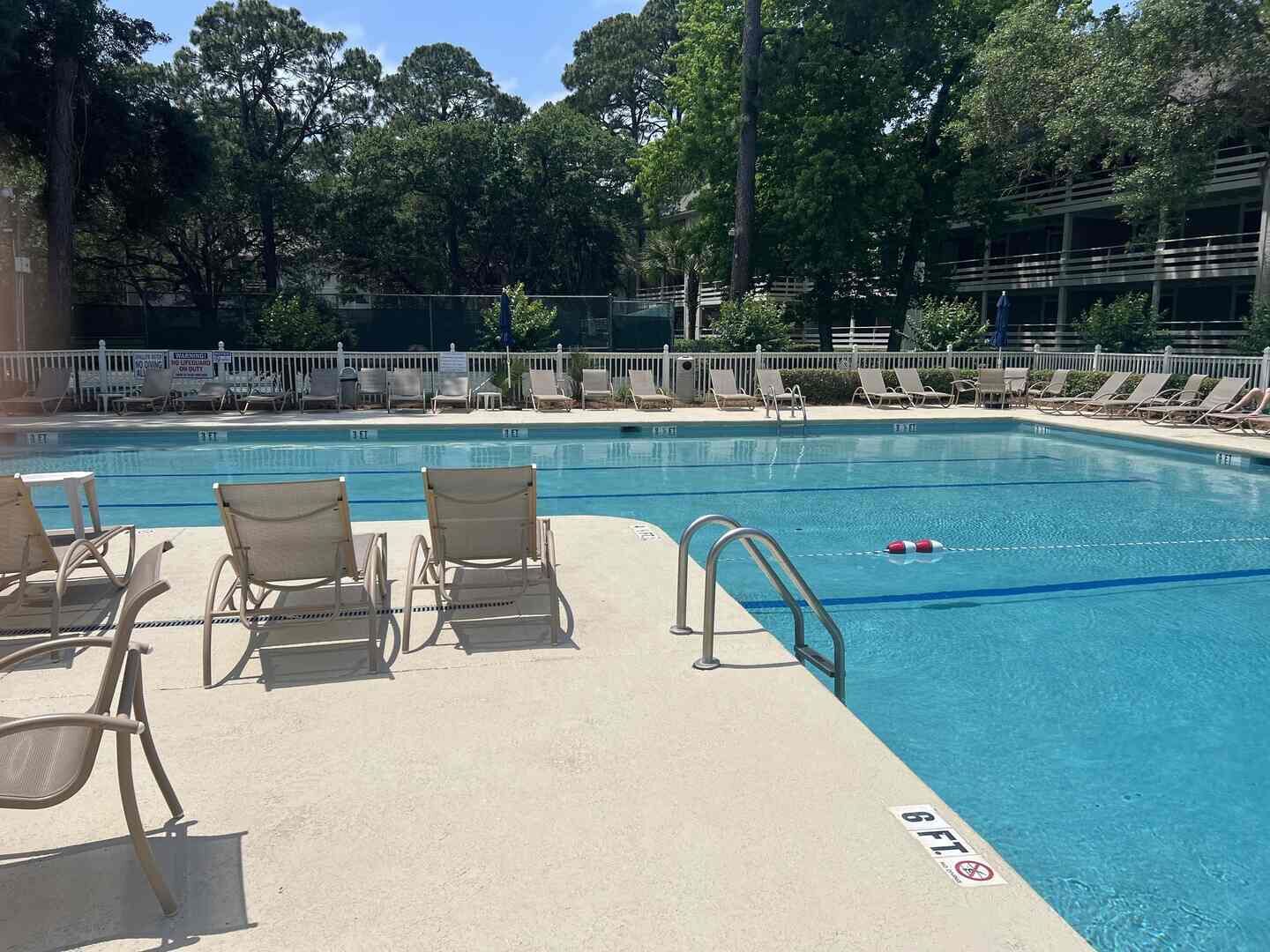 Une piscine avec des chaises longues et un poste de surveillance pour les sauveteurs.