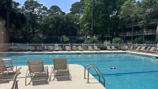 A swimming pool with lounge chairs and a lifeguard stand. - Fiddlers Cove Gated Resort- Pools- Hot Tub - Tennis - Pickle Ball walk to Beach! (Hilton Head Island)