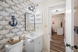 Ein Badezimmer mit Toilette, Waschbecken, Spiegel und Wandpapier mit Muster.
