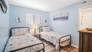 A bedroom with two beds, a window with blinds, a nightstand with a lamp, and a painting on the wall. - Fiddlers Cove Gated Resort- Pools- Hot Tub - Tennis - Pickle Ball walk to Beach! (Hilton Head Island)