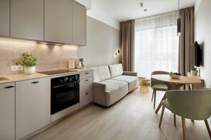 Una cocina moderna con horno empotrado, un comedor con mesa y sillas, y un sofá.