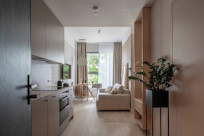 Una cocina moderna con electrodomésticos integrados, una zona de comedor con mesa y sillas, un sofá y una planta en maceta.