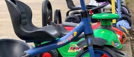 Una hilera de triciclos infantiles estacionados al aire libre.
