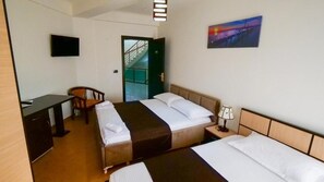 Una habitación de hotel con dos camas, un escritorio, una silla, un televisor y un cuadro en la pared.