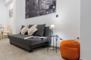 A modern living room with a grey sofa, a lamp, and a cityscape painting. - Luxurious apartment with a patio in downtown Seville (Sevilla)