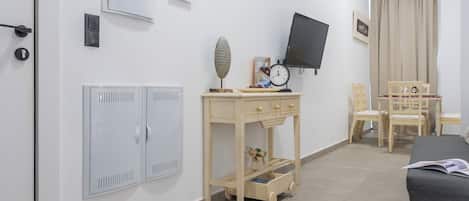 A room with a bed, a TV, a desk with a clock, and a wardrobe.