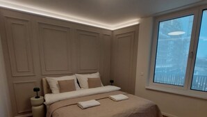 Ein Schlafzimmer mit Bett, Nachttisch, Fenster und Deckenleuchte.